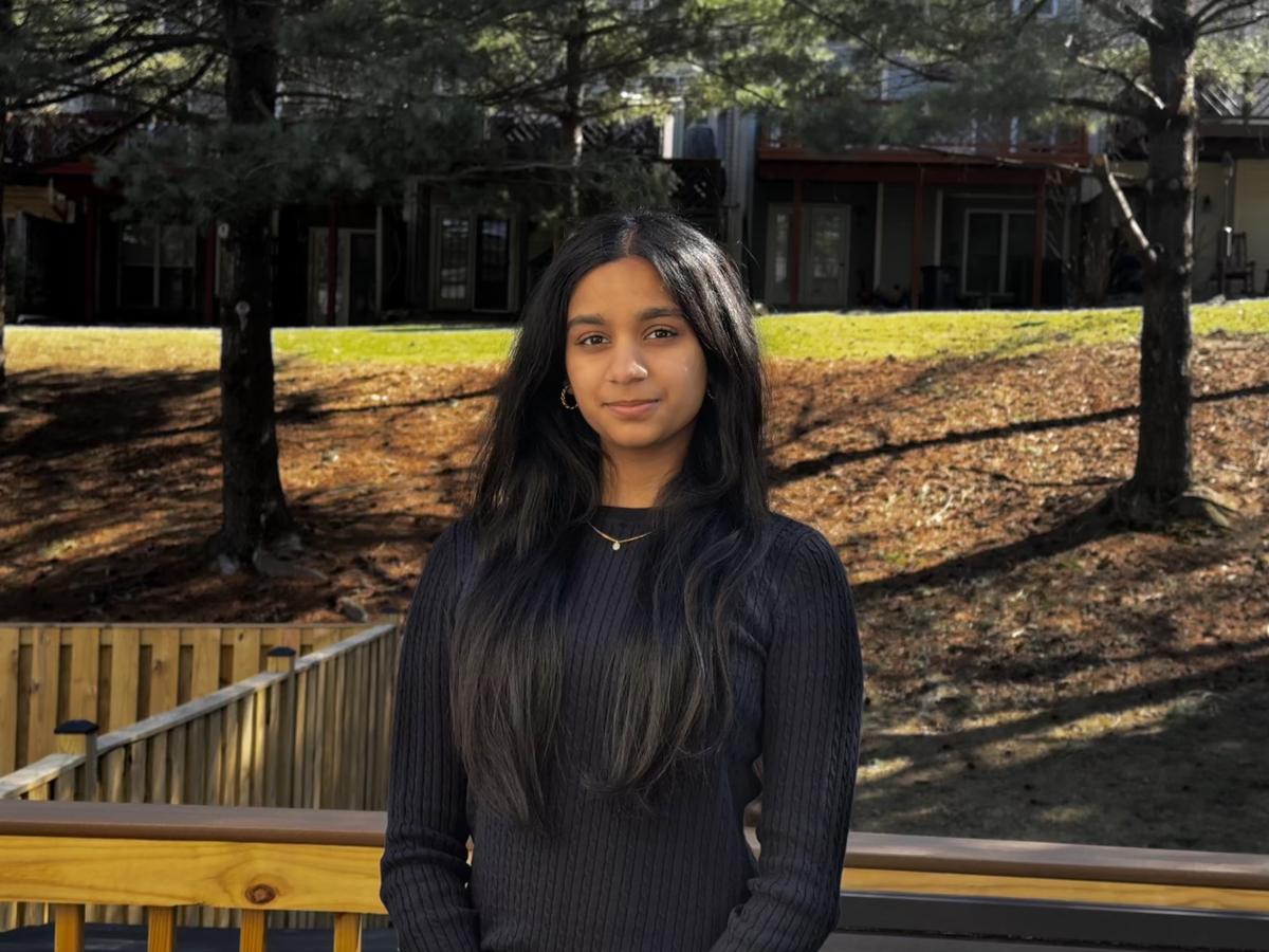 Aditi with brown mulch and trees behind