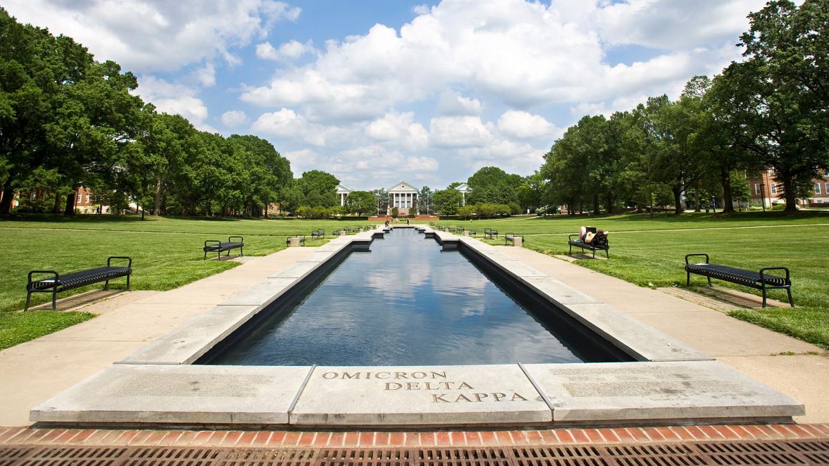 View of ODK Fountain on the Mall, looking towards Main Administration Building. Blue sky, clouds, green grass/trees.